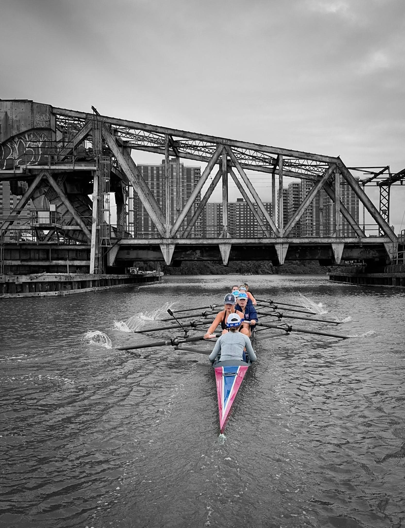 A sculler in black and white beneath the bridge