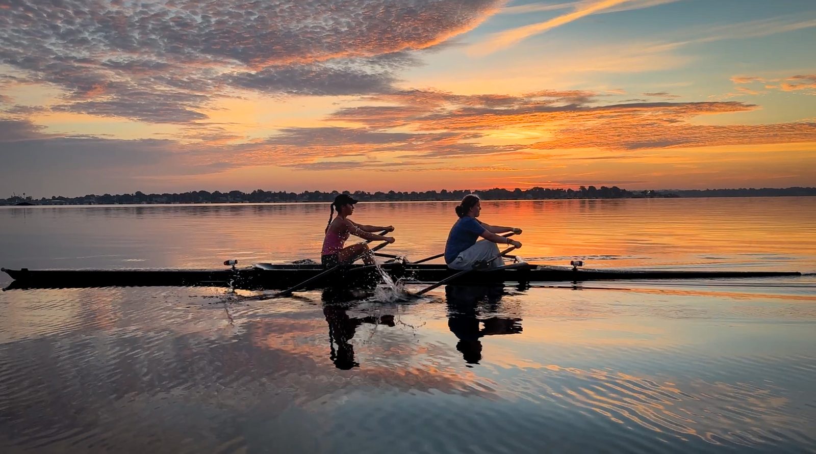 A pair paused on glass water under a sunrise sky