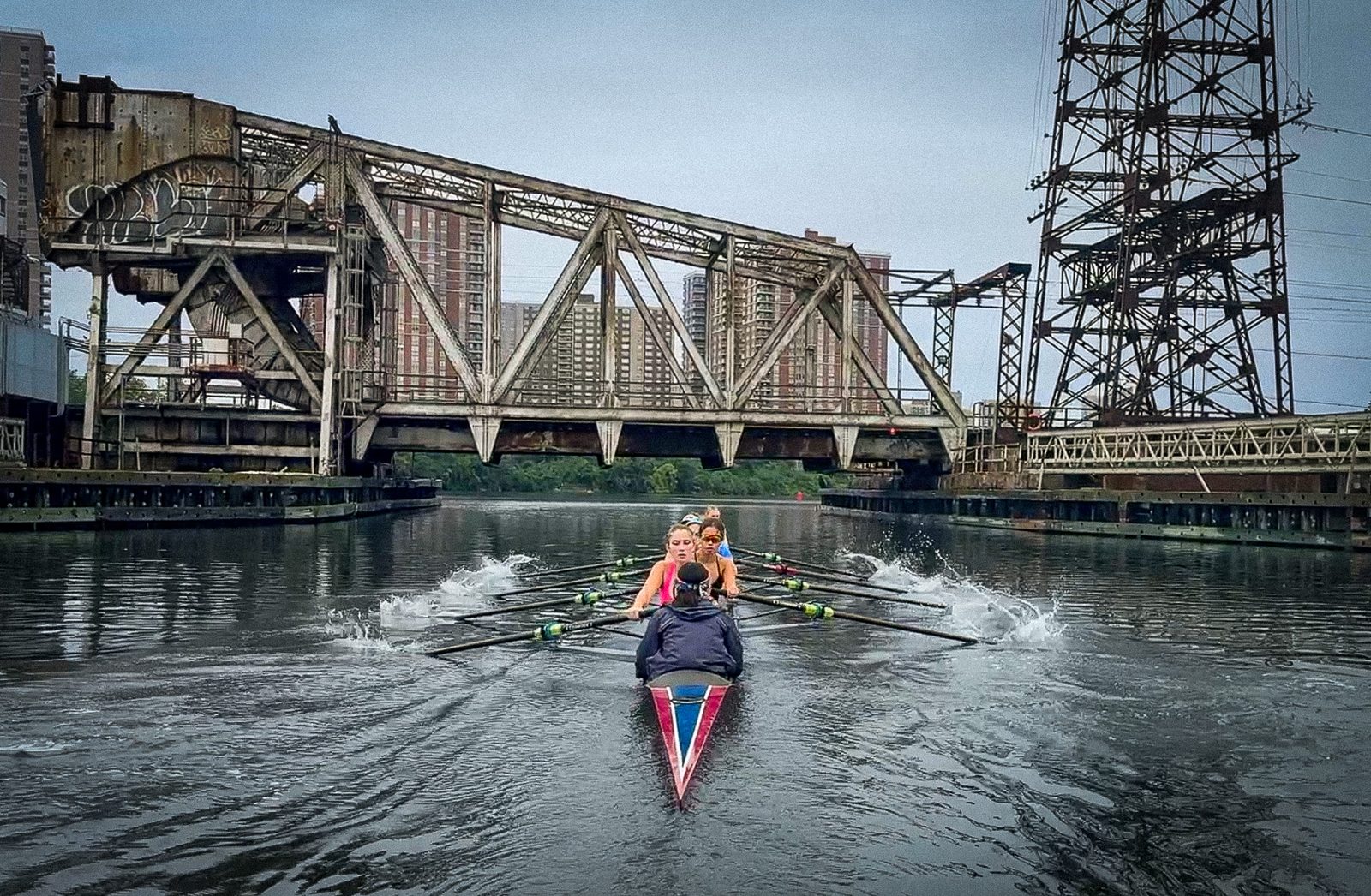 A sculler rowing beneath the old iron bridges