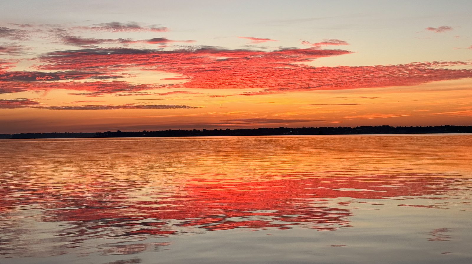 Red and orange sky reflected across the whole width of the water