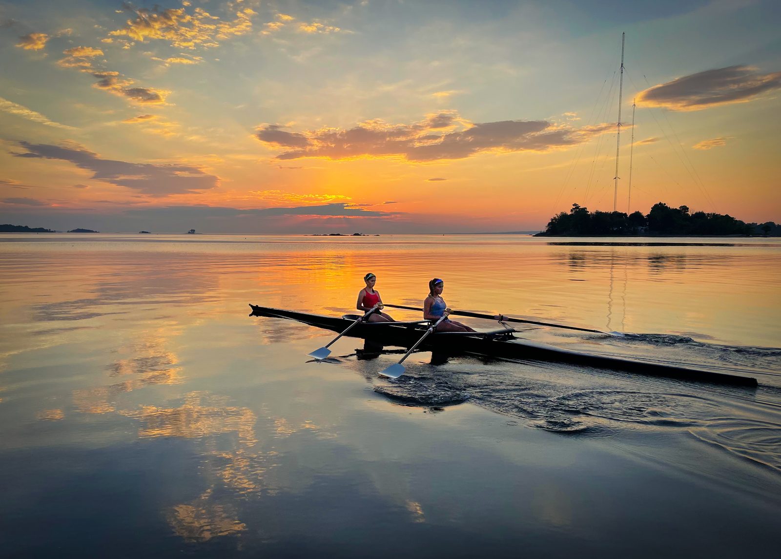A double scull on glass-calm water under a golden evening sky
