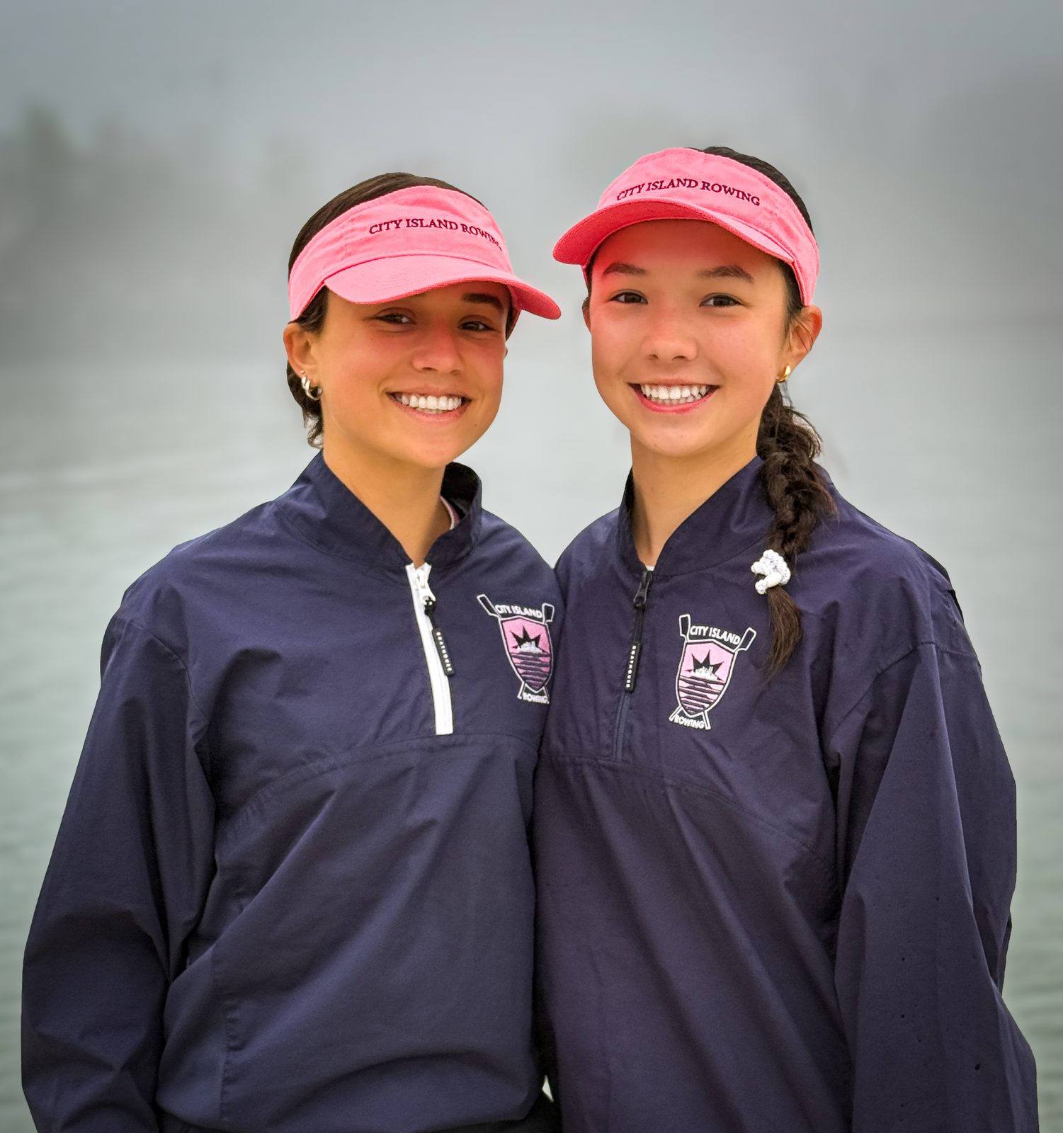 Two teammates in pink visors, all smiles on a foggy morning