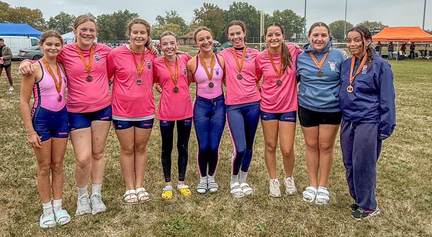 A group of City Island Rowing girls in pink on the regatta field, medals around their necks